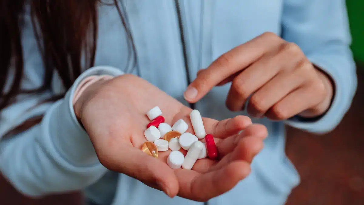 Woman’s hands counting assorted pills. Synthetic opioid abuse has played a significant role in the opioid crisis in the United States.