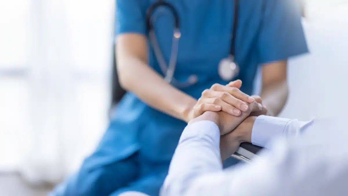 Doctor in blue scrubs comforting a patient.