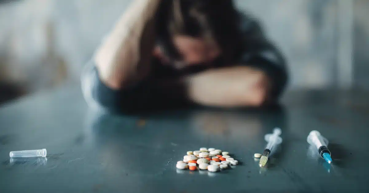 Teen boy in a black hoodie with his head resting in his hand. Superimposed text explains the five factors leading to drug abuse.