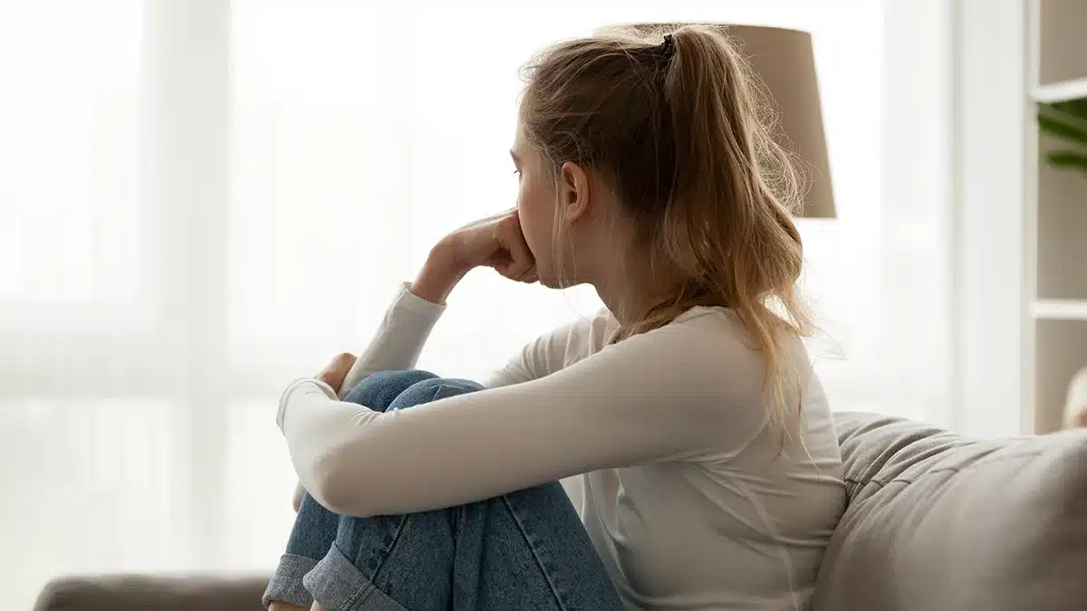 depressed woman looking out a window