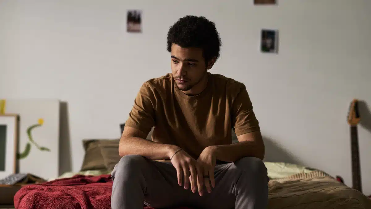 depressed man looking down on the side of his bed